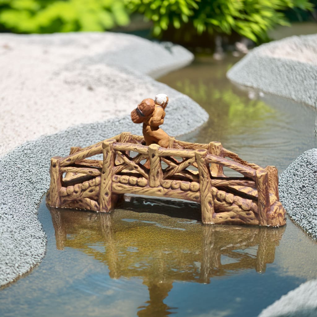 Brown fairy garden bridge with log-like railings over water; a garden mini bridge.
