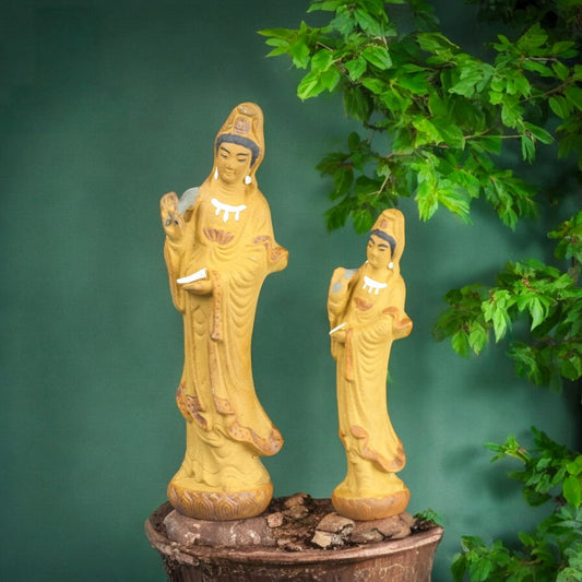 Two yellow Ceramic Guan Yin Statue figurines, large and small, on a bonsai. Kwan Yin figurine.