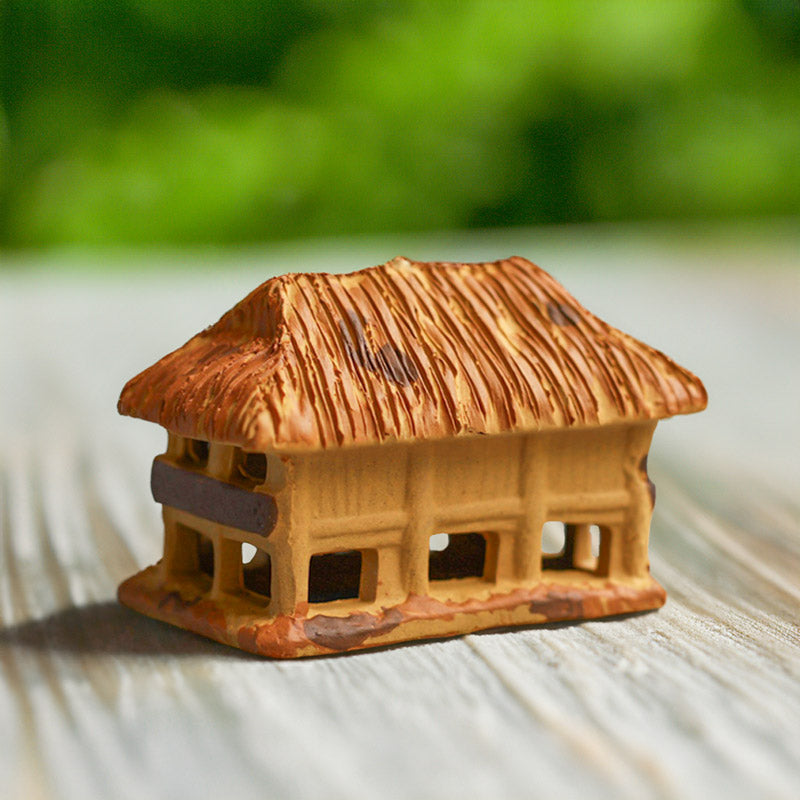 A handcrafted miniature stilt house, made from earthy brown ceramic, showcases the unique architectural style of Vietnam, adding a touch of cultural charm to any bonsai display.