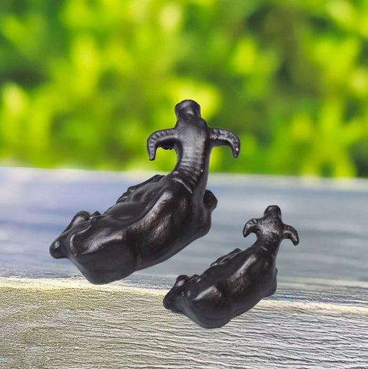 Two black Ceramic Water Buffalo Statues, a set of animal figurines, are viewed from behind sitting on a wooden surface. Use these as bonsai figurines or terrarium decor.
