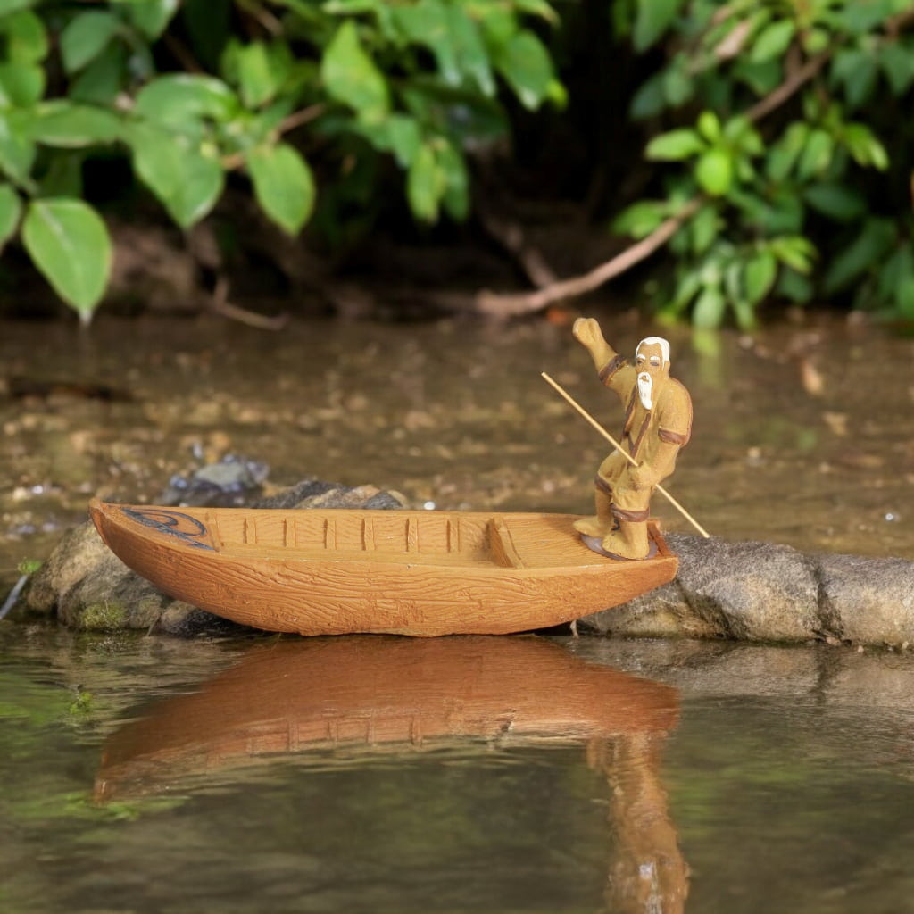 A ceramic figurine of an old fisherman rowing a wooden boat.