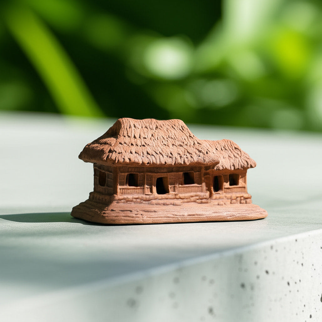 A brown thatched house figurine, viewed from the side, shows its textured roof. This mini house figurines is compact.