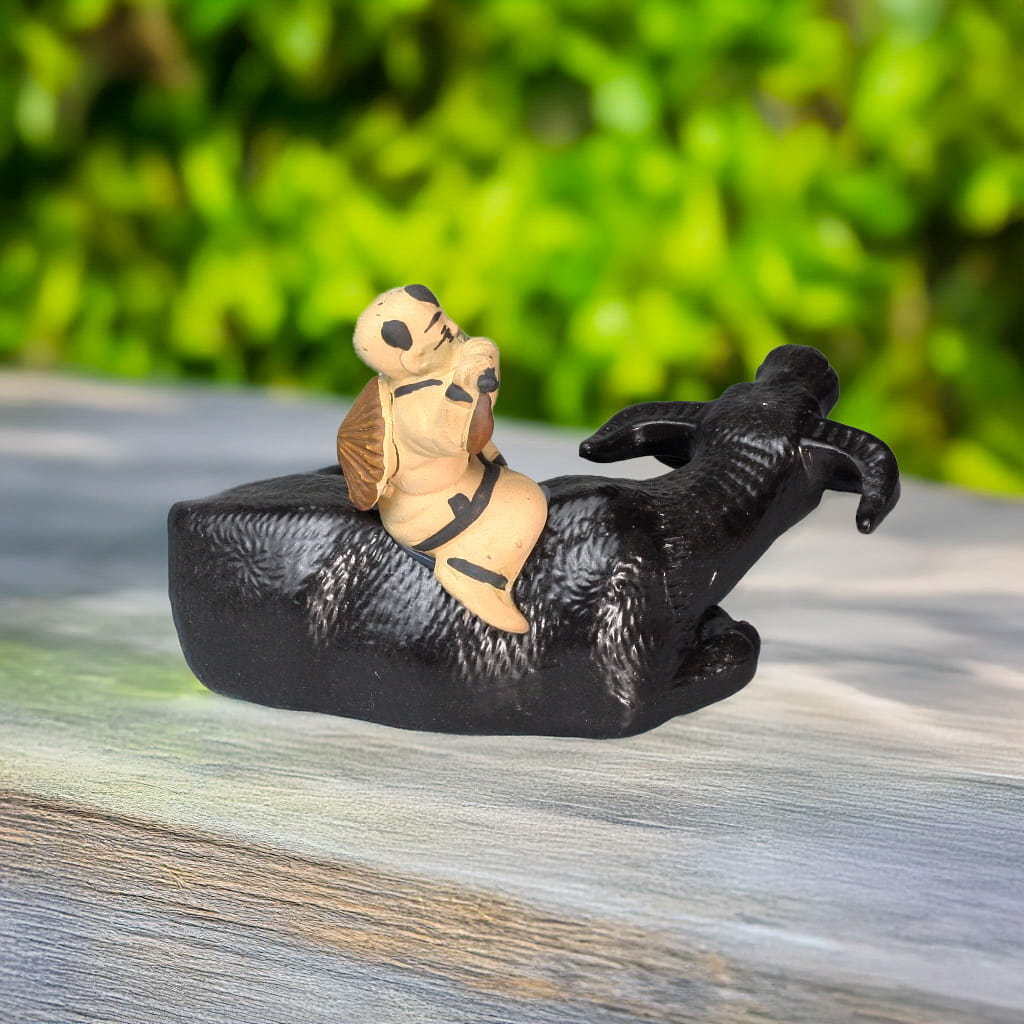 Rear view: boy on a cute water buffalo. This charming buffalo sculpture is detailed.