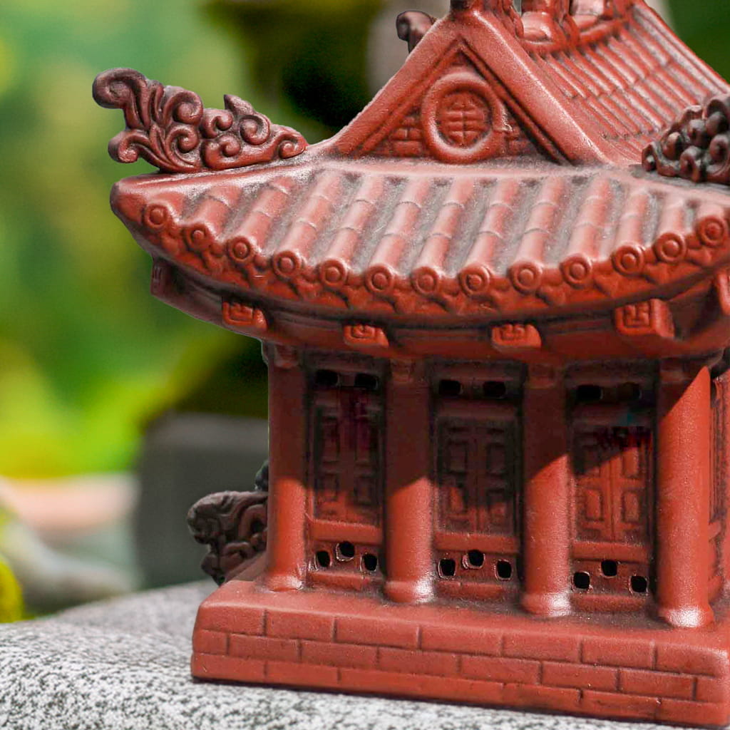 Close-up of reddish-brown miniature pagoda roof and wall. Ornate bonsai figurines detail.