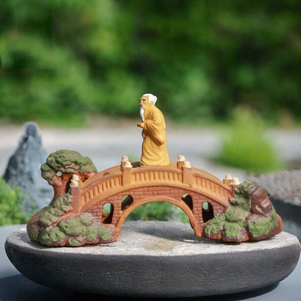 Mudman on a fairy garden bridge. This garden mini bridge is on a flat bonsai pot.