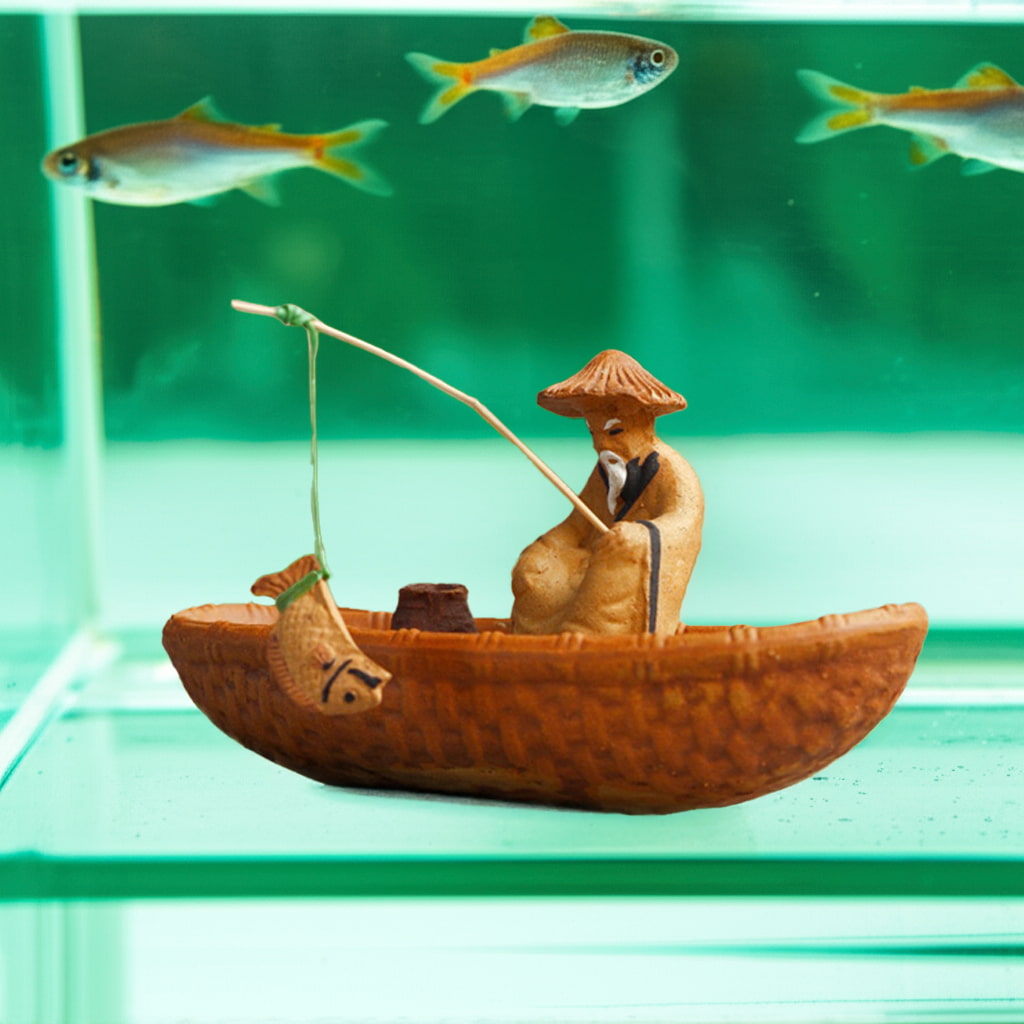 A fishing man figurine in a small boat floats in an aquarium with fish, ideal bonsai decoration.