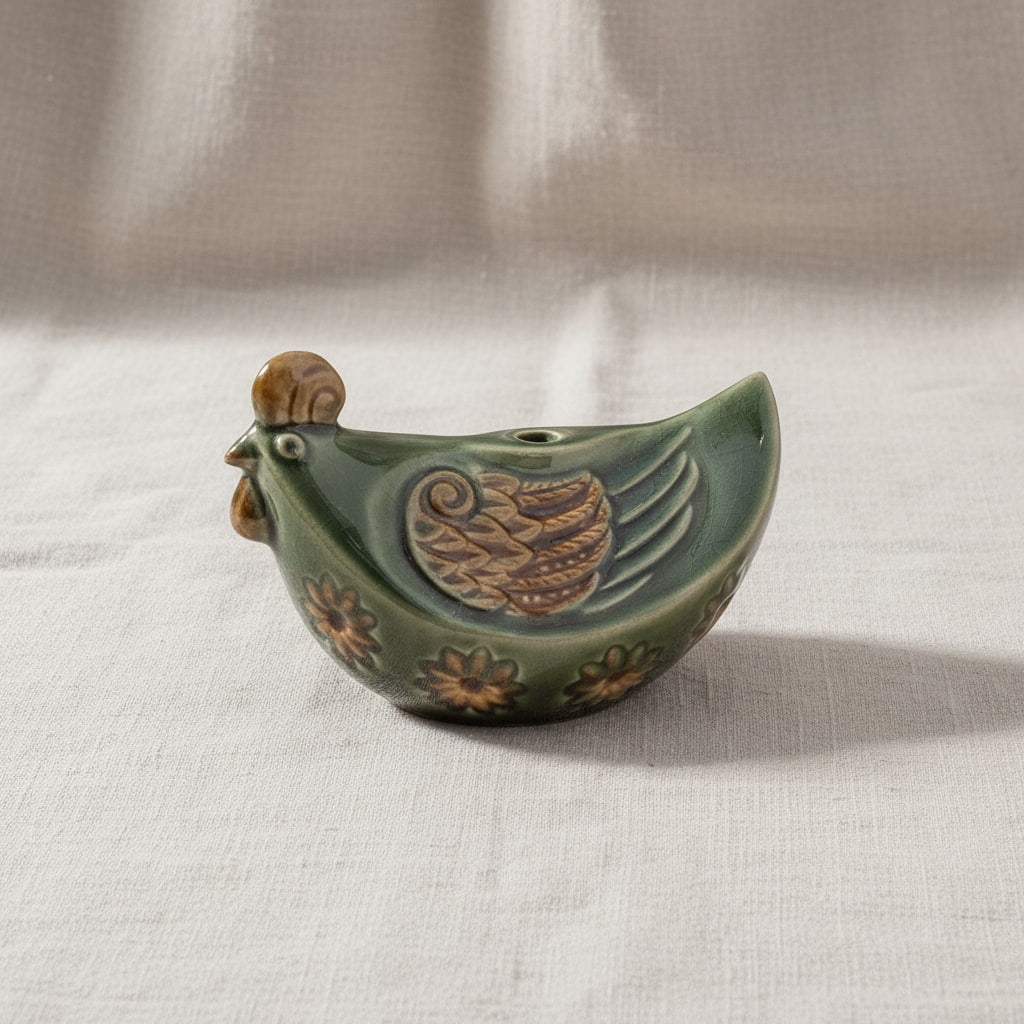 A side view of a green Vietnamese pottery rooster. This is a hand-painted rooster ceramic figurine