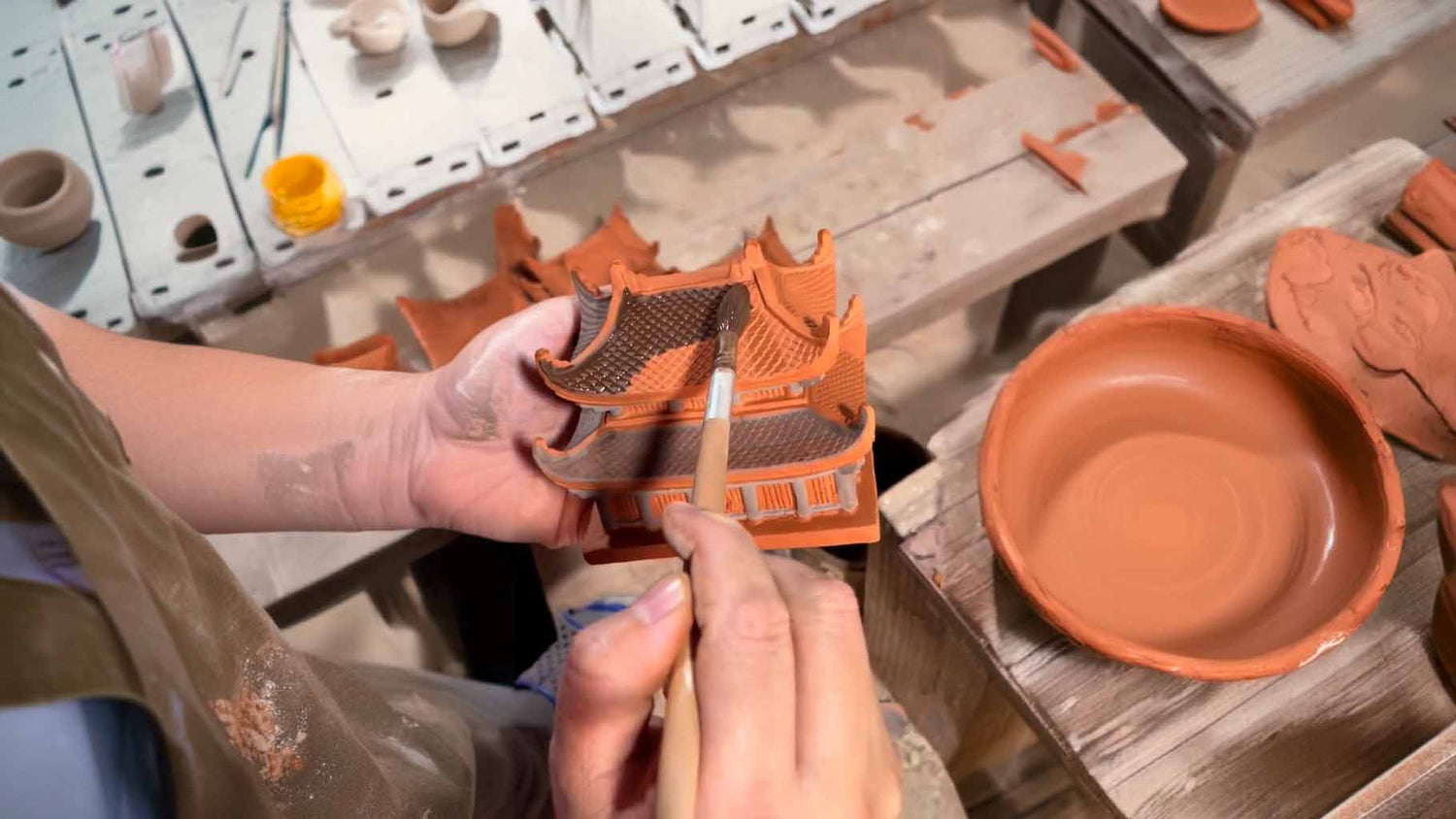 In the heart of Bat Trang village, a skilled artisan meticulously hand-paints a miniature ceramic pagoda, showcasing the dedication and artistry behind each Vietnamese ceramic statue.