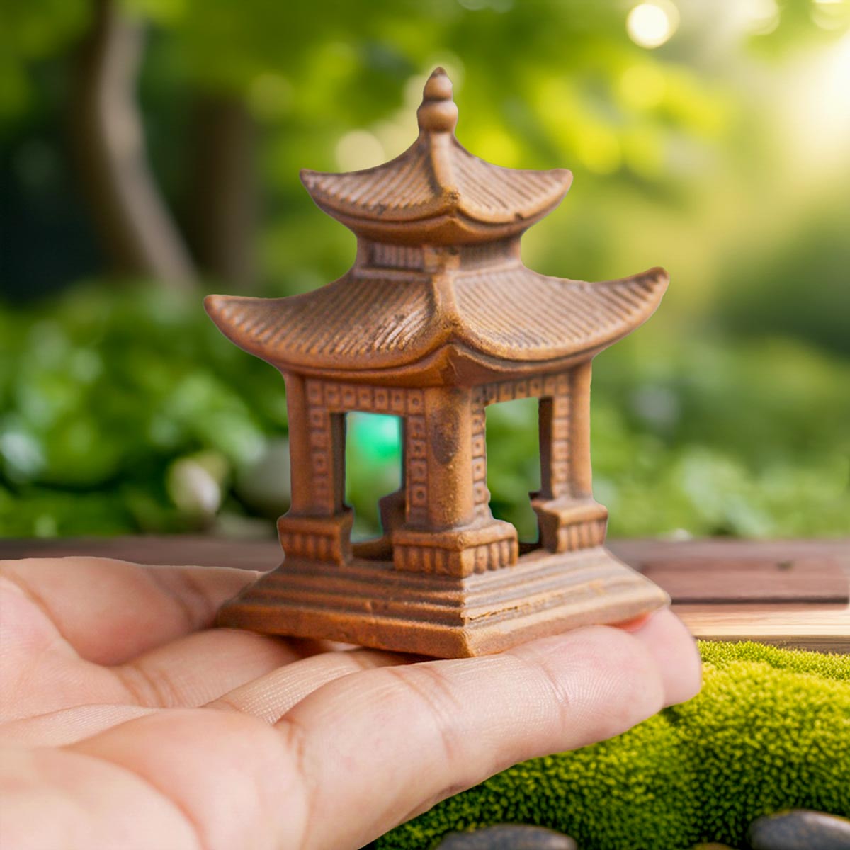 Hand holds a brown miniature Japanese pagoda. A handcrafted pagoda statue for Zen garden decor.