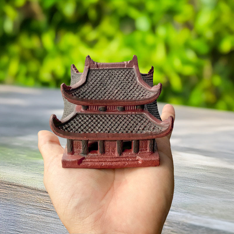 Hand holds a miniature pagoda statue showing its size. It's a ceramic Vietnamese pagoda.