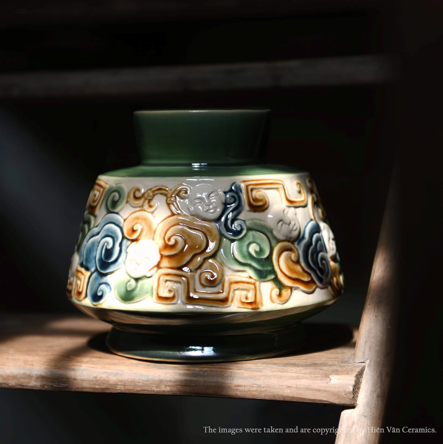 A handmade in Vietnam vase. This green centerpiece ceramic vase shows a detailed cloud motif.