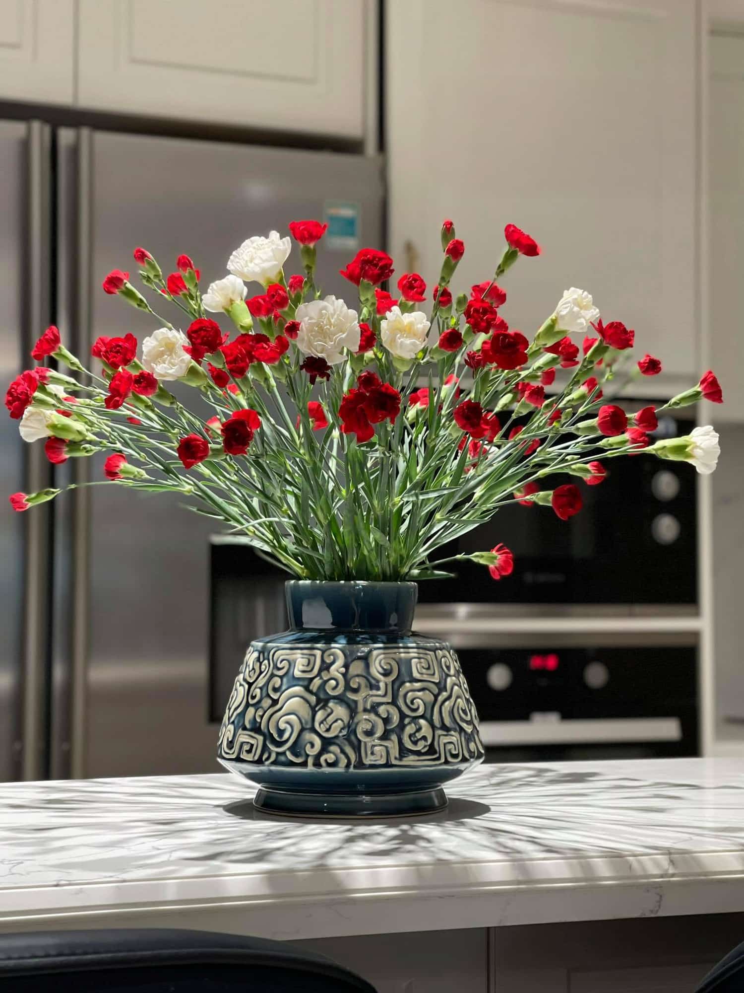 This low wide flower vase, an artisan vase for a kitchen island, holds red & white flowers.