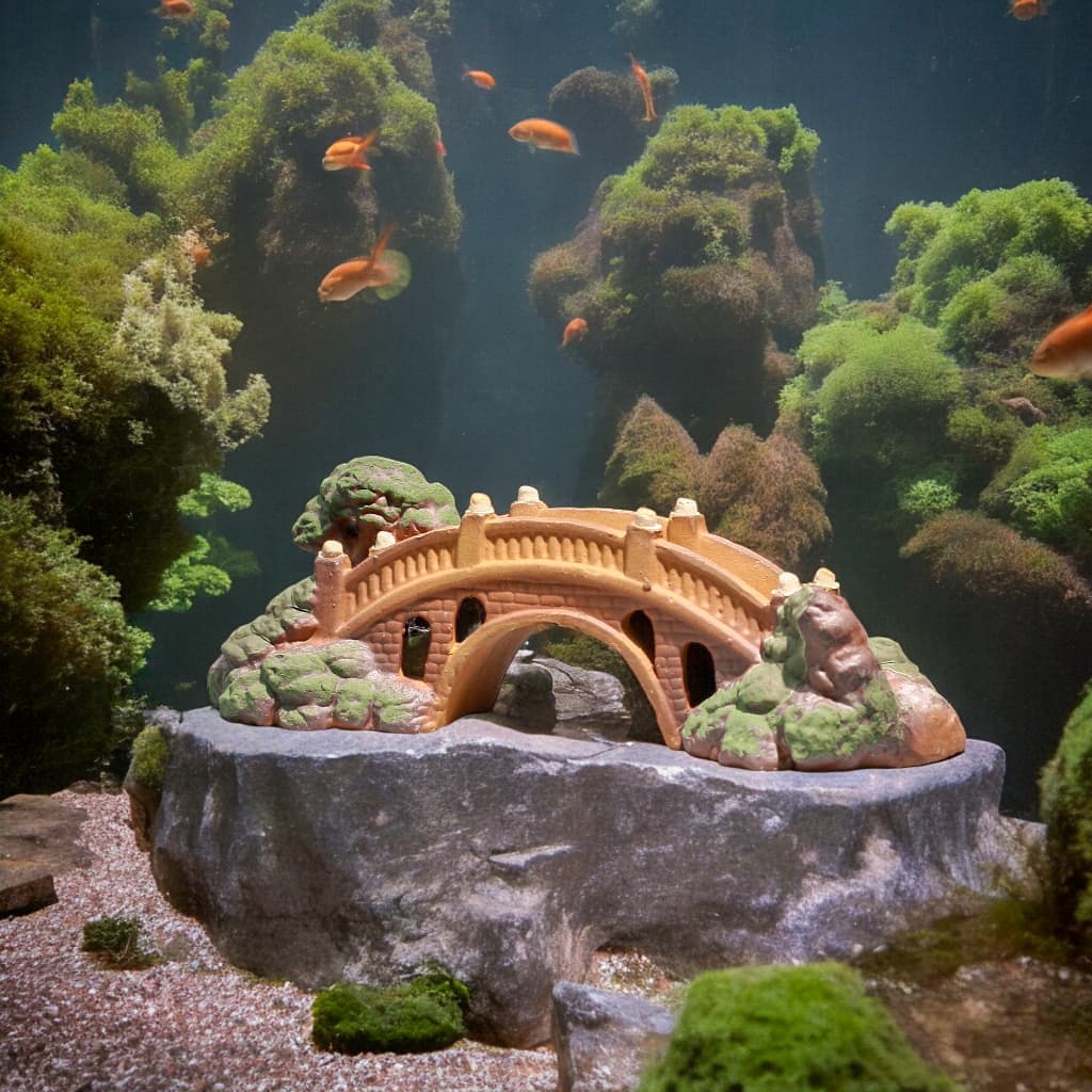 An orange arched miniature bridge sits on a rock in an aquarium, a Bonsai Bridge style.