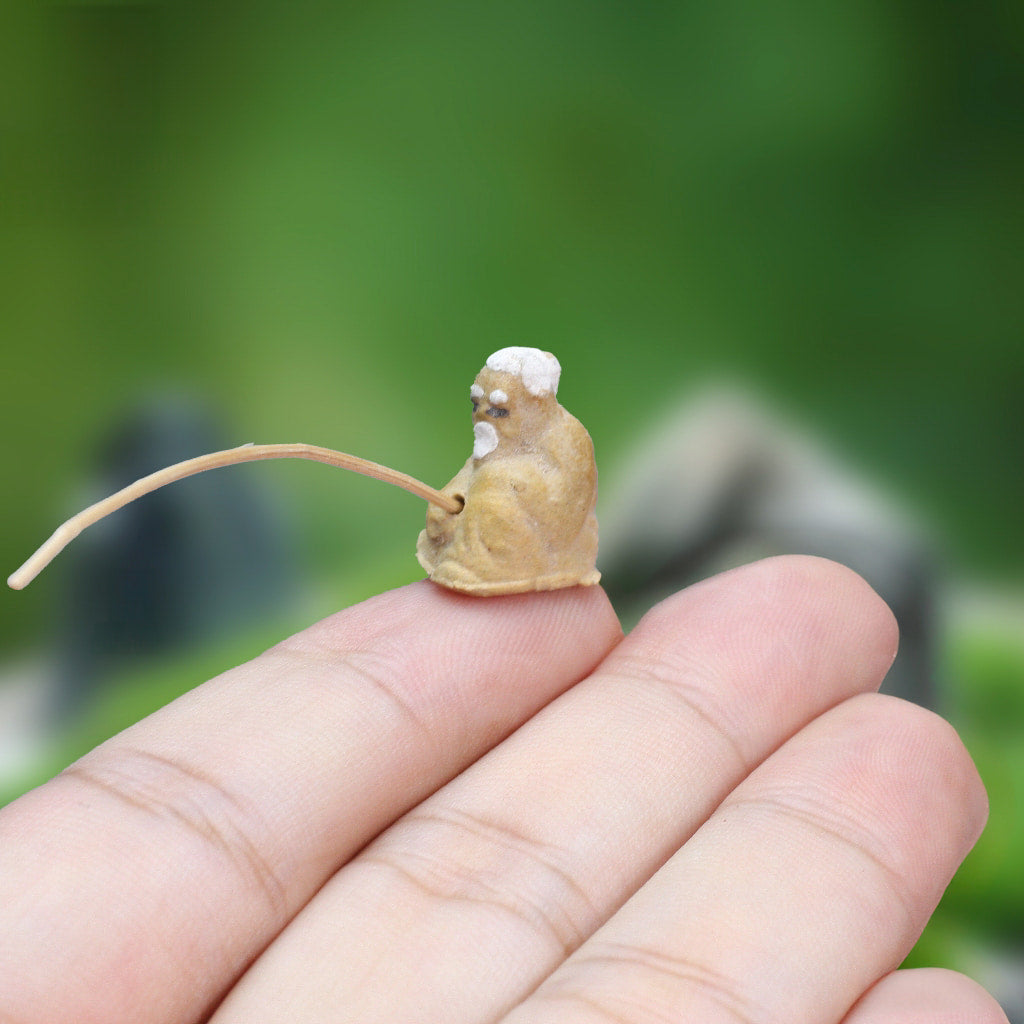 A miniature ceramic mudmen fisherman figurine perched on a person's hand
