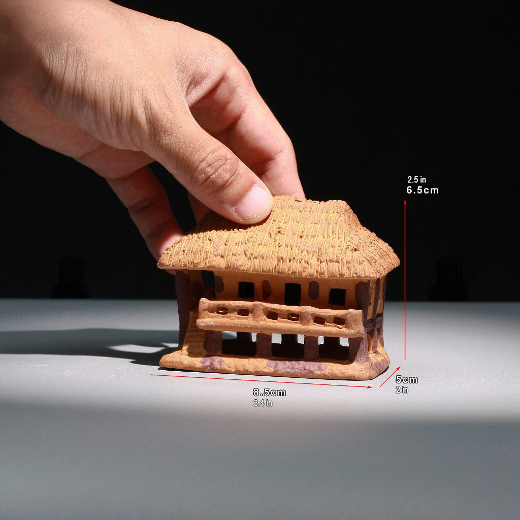 Hand holds brown vietnamese stilt house figurine, part of Ceramic Houses Villages line