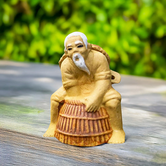 A miniature Vietnamese Mudman, his weathered face reflecting years spent under the sun, patiently awaits a catch with his traditional basket trap.