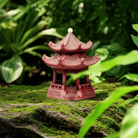 A reddish miniature pagoda, a serene ceramic pagoda statue, rests on a mossy rock in a green garden.