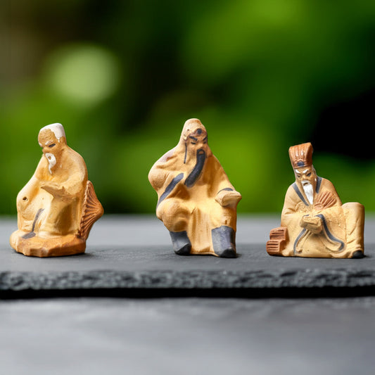 Three assorted bonsai mudmen sit in a row. These Chinese mudmen figurines are unique bonsai decor.