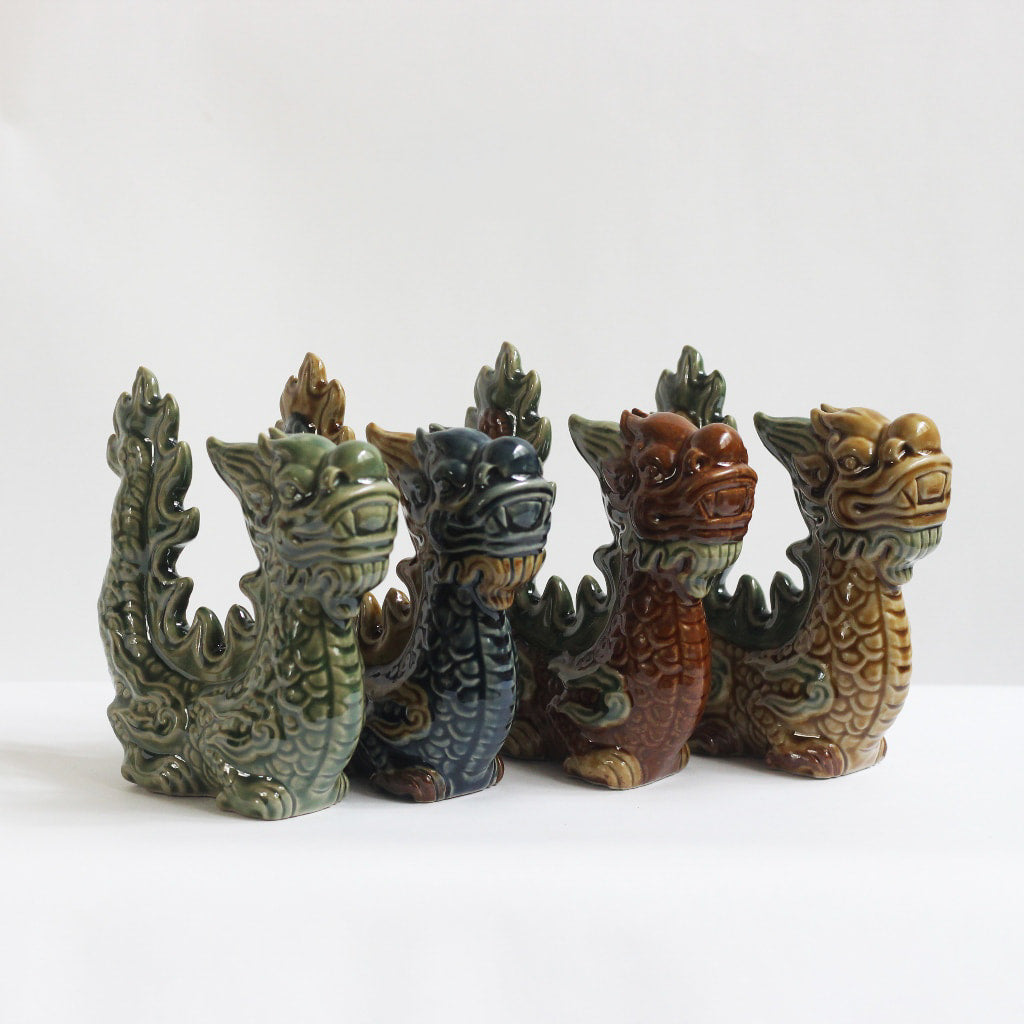 Four Vietnamese ceramic dragon figurines in green, blue, red, and brown glazes stand together.