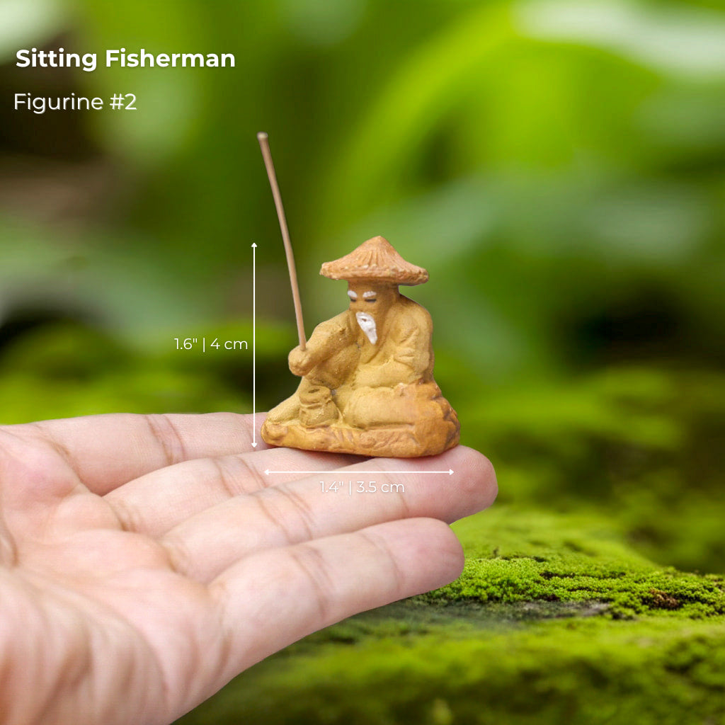 A tiny Sitting Fisherman bonsai mudmen figure in hand. It's a detailed bonsai figurine.