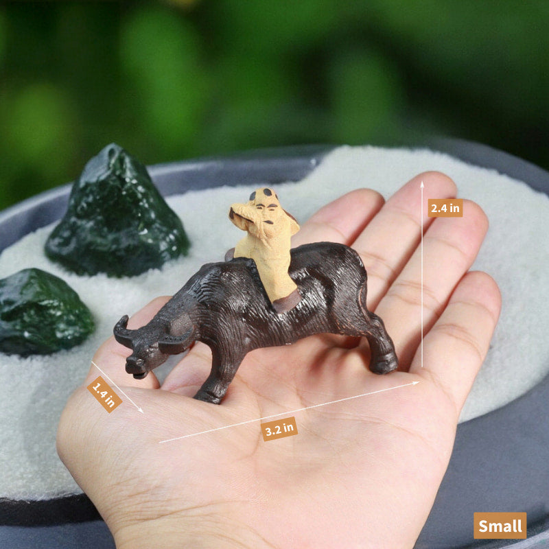 A small, dark brown ceramic water buffalo statue with a boy riding on its back is held in a hand.