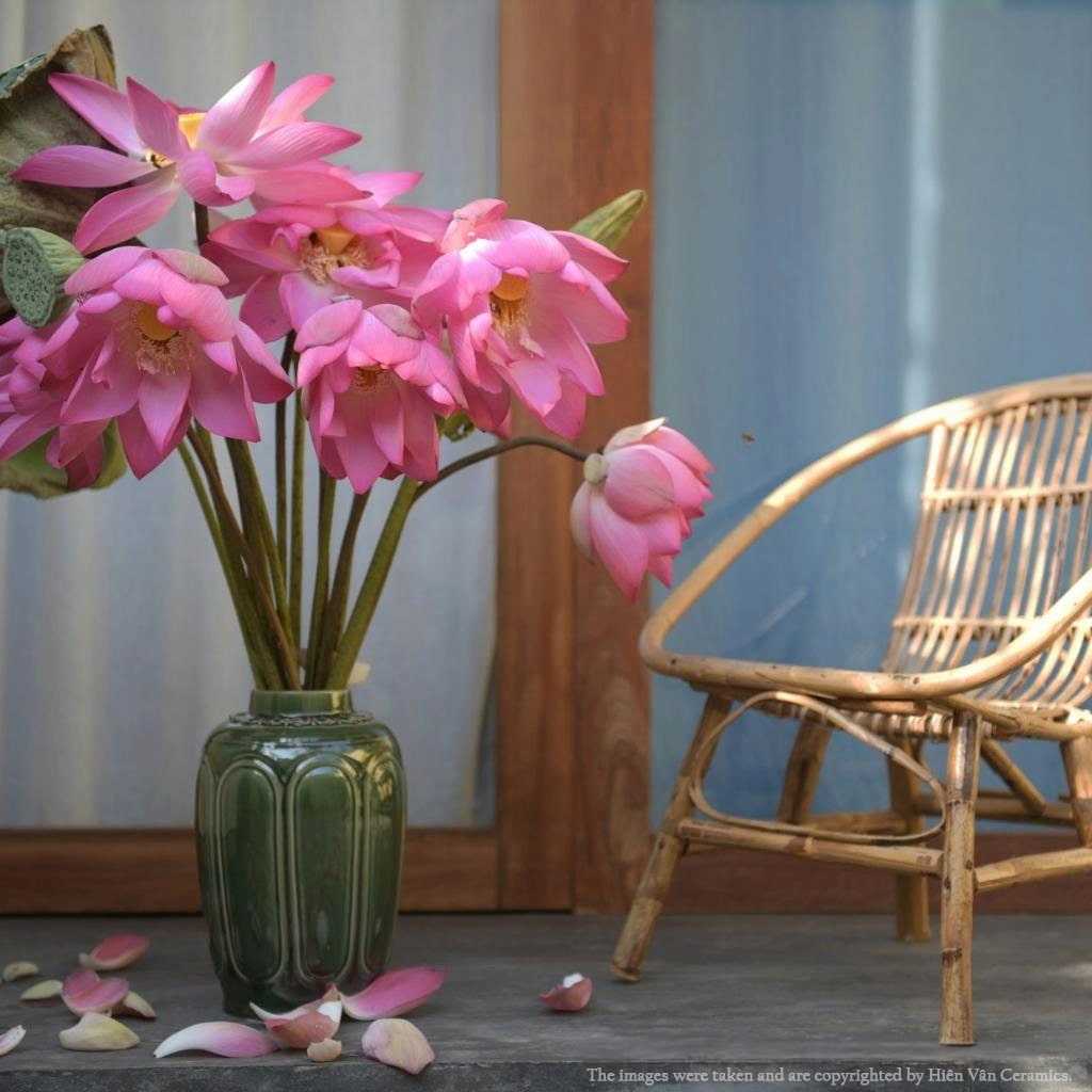 A green handmade vietnamese vase with pink lotus, a piece of traditional vietnamese pottery.