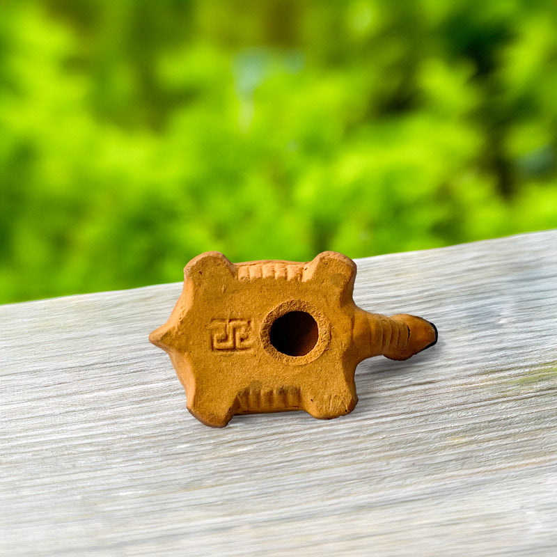 The intricate details of a miniature ceramic turtle are revealed from behind, showcasing the handcrafted artistry of Vietnamese artisans.