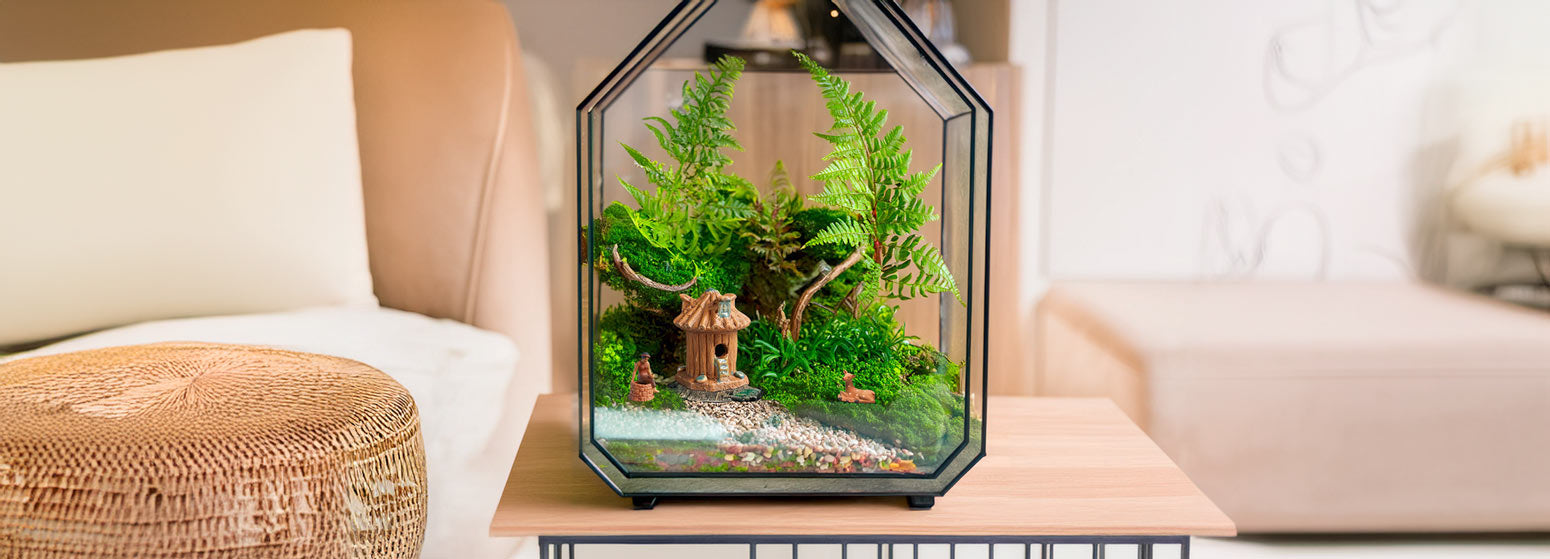 Inside a geometric glass terrarium, a miniature Vietnamese stilt house nestles amongst ferns and moss, while a tiny mudman figurine stands nearby, creating a serene and enchanting scene.