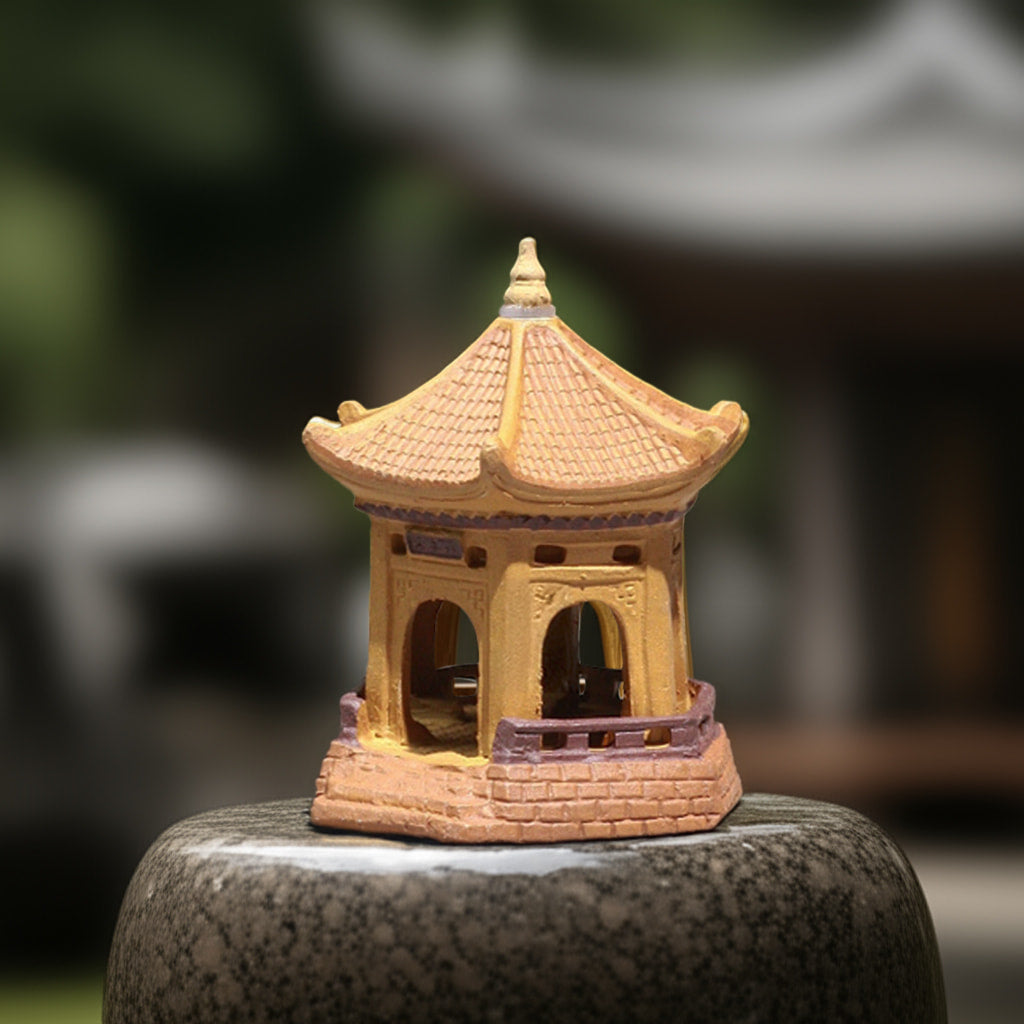 A yellow miniature pagoda sits on a stone base. It's a striking pagoda statue, perfect bonsai pagoda decor.