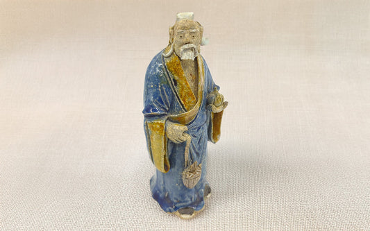 A small blue-robed man figurine, symbolizing the rich heritage of Mudmen artistry and tradition.