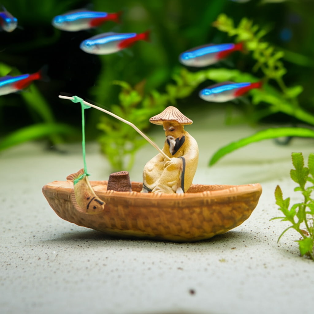 Miniature fisherman figurine in a boat on aquarium sand. Colorful fish swim. Ceramic fisherman figure for Aquarium Decor