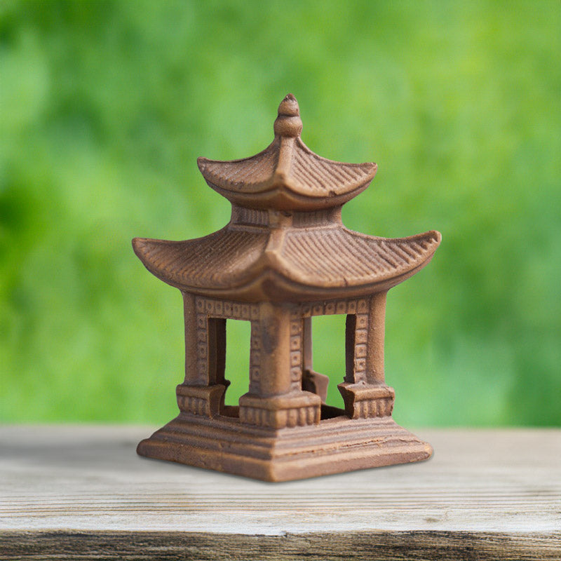 Small Ceramic japanese pagoda figurine on a wooden surface with a blurred green background