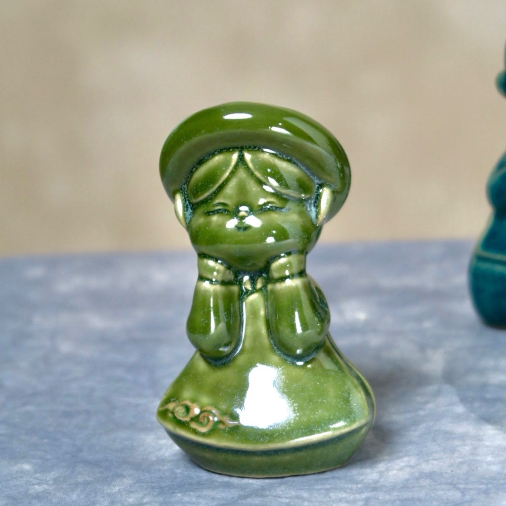 Green-glazed seated Vietnamese boy figurine in ao dai, close-up