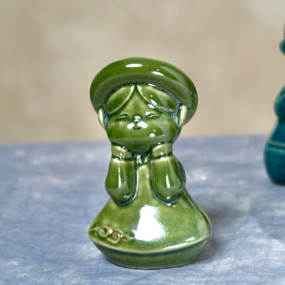 Green-glazed seated Vietnamese boy figurine in ao dai, close-up