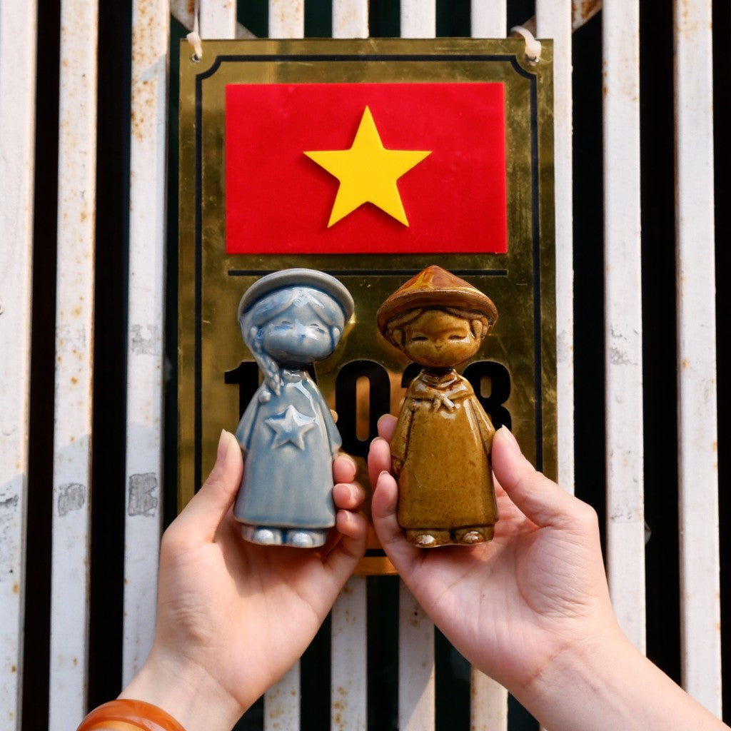 Hands holding a blue star child and amber boy Vietnamese ceramic figurines
