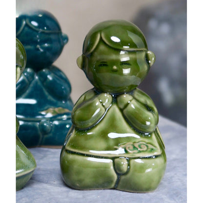 Close-up of a green-glazed seated Vietnamese boy figurine in ao dai