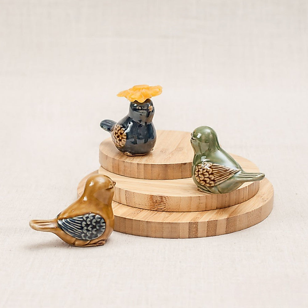 Three Vietnamese ceramic bird figurines displayed on a tiered wooden stand
