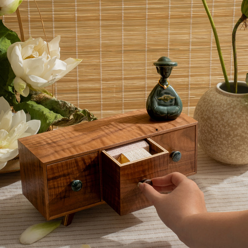Small duck-green Vietnamese woman figurine on a wooden drawer box