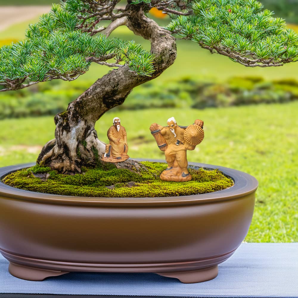 Two miniature ceramic figures, one sitting and one standing, are placed beneath a bonsai tree. The figures depict woodcutters, one resting and one carrying firewood.
