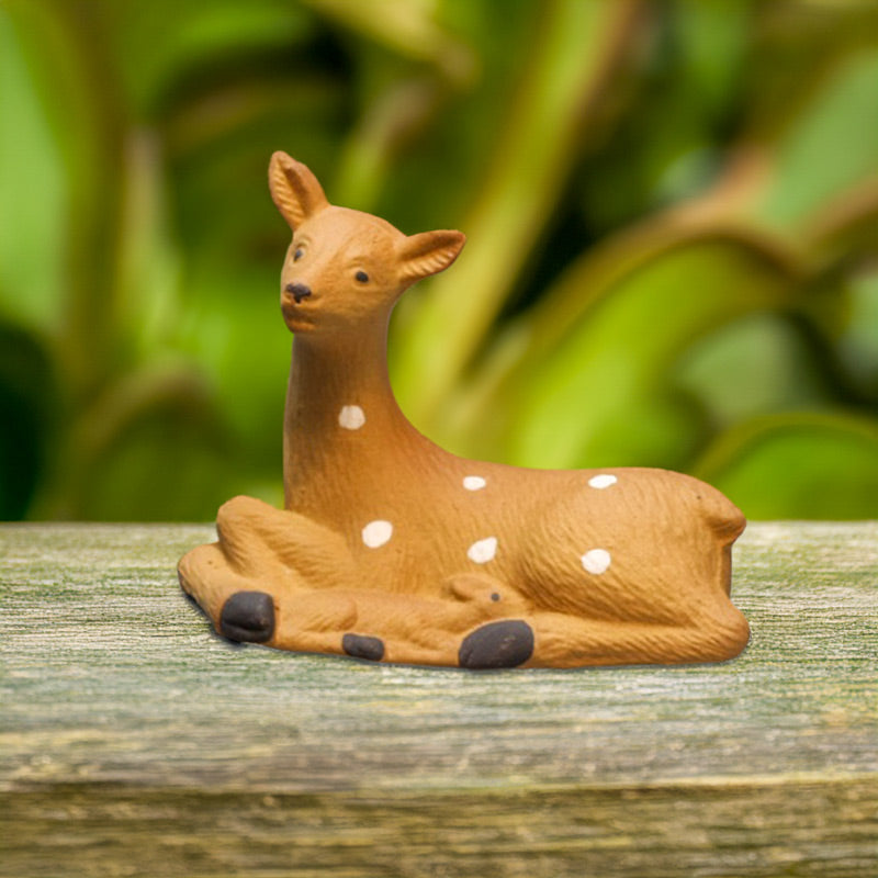 A charming ceramic mother deer, with her fawn nestled beside her, gazes serenely forward, adding a touch of whimsy to any miniature garden.