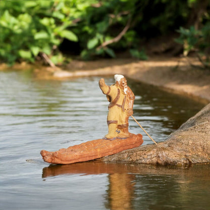 A figurine of a man fishing from a raft, surrounded by water, titled "Fisherman on Raft."