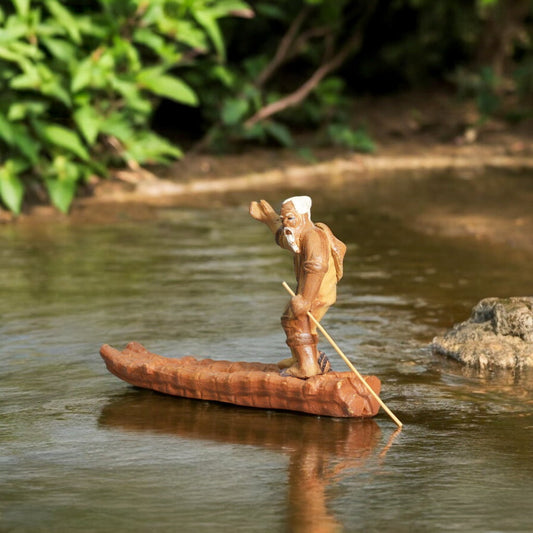 Ceramic figurine of an old fisherman in a raft, depicting a serene scene on the water.