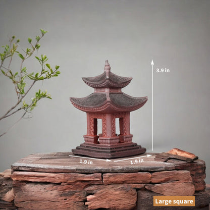  A large, square Japanese pagoda made from red clay stands on a stone platform. The multi-tiered structure features intricate carvings and a weathered appearance.