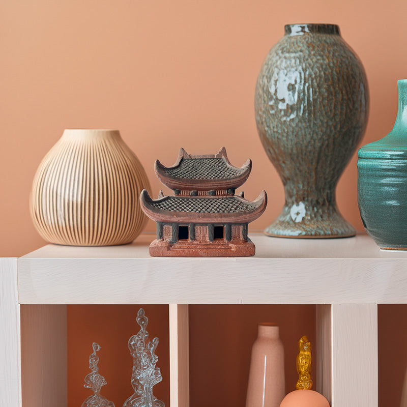 This elegant ceramic pagoda, with its distinctive tiered roof and intricate detailing, adds a touch of cultural charm to this stylish home decor display.