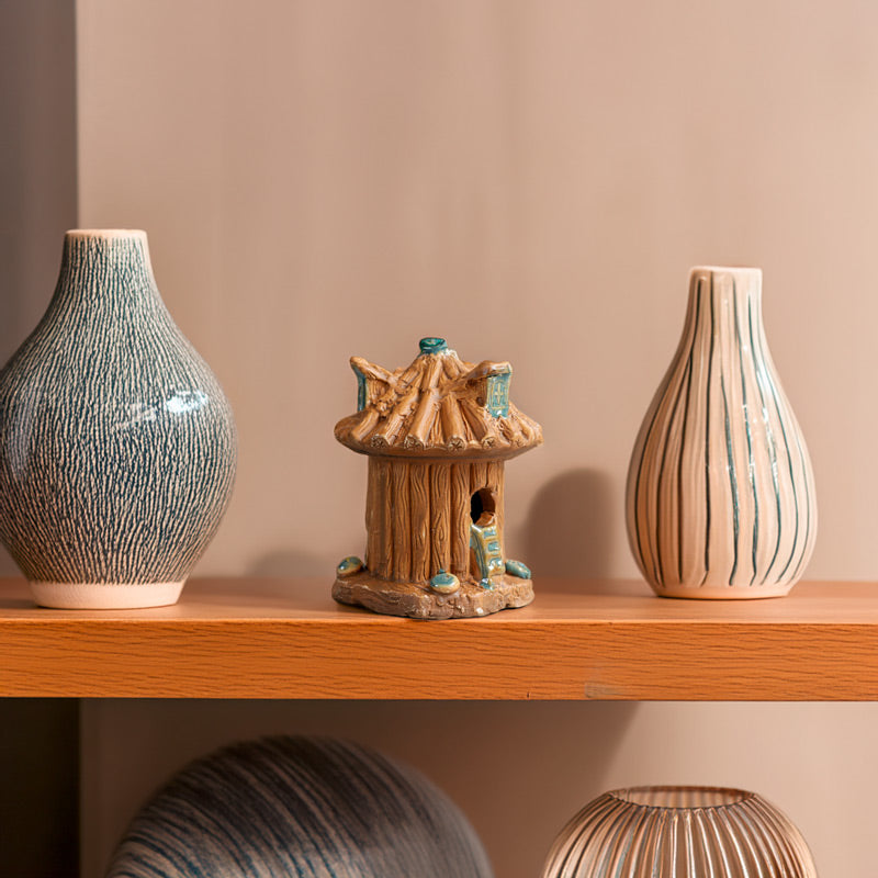 Adding a touch of enchantment to a minimalist shelf, a ceramic treehouse, with its earthy tones and charming details, stands out as a unique piece of art for any home.