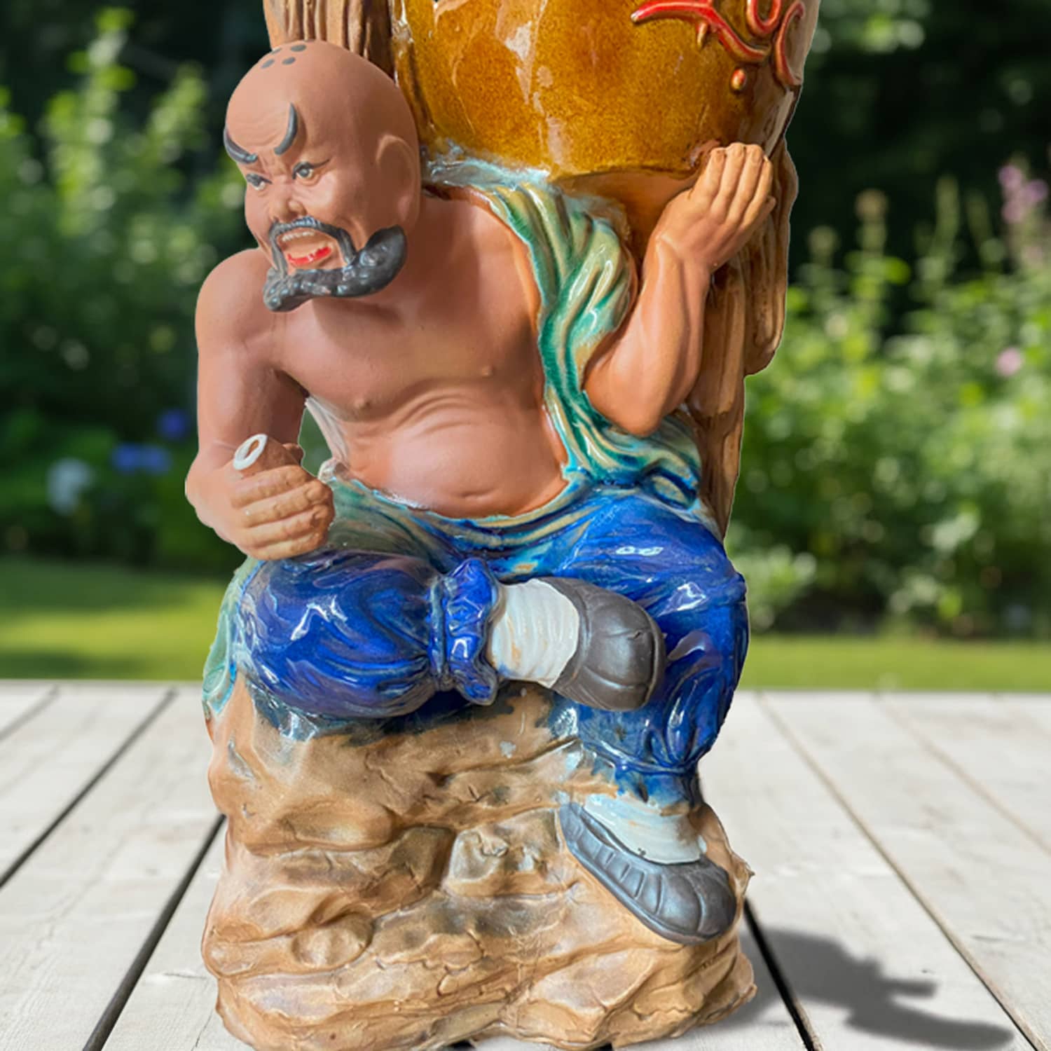 A close-up of the ceramic figurine pot showing the detailed face of the statue bonsai planter.