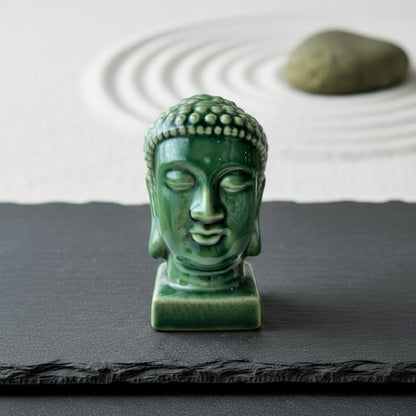 An emerald buddha head statue on slate in a zen garden. Serene green buddha statue decor