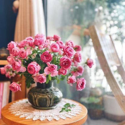 A green low wide flower vase filled with pink roses. A perfect handmade ceramic flower vase for decor.