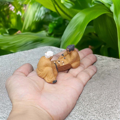 Resting in the palm of a hand, two miniature mudmen, engaged in a game of chess, showcase the intricate detail and delicate artistry of these handcrafted figurines.