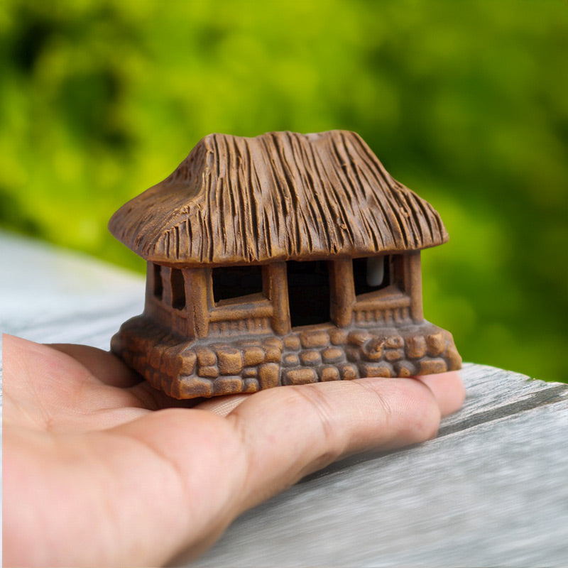 Held gently in the palm of a hand, a miniature thatched house, meticulously crafted from ceramic, reveals the intricate details of this traditional Vietnamese home.